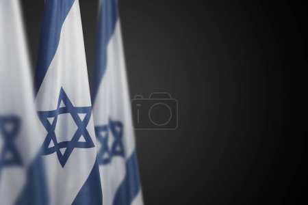 Israel-Fahnen mit einem Davidstern auf dunkelgrauem Hintergrund. Patriotisches Konzept über Israel mit Nationalstaatsymbolen. Banner mit Platz für Text.