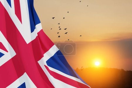 Téléchargez les photos : Drapeaux nationaux du Royaume-Uni avec des oiseaux volants sur fond de ciel couchant. Contexte avec place pour votre texte. Rendu 3d. - en image libre de droit