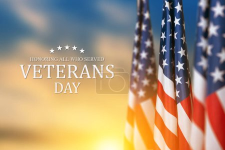 Foto de Banderas estadounidenses con texto Día de los veteranos honrando a todos los que sirvieron en el fondo de la puesta del sol. Banner de vacaciones americano. - Imagen libre de derechos