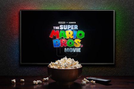 Photo for TV screen playing The Super Mario Bros. Movie trailer or movie. TV with remote control and popcorn bowl. Astana, Kazakhstan - March 23, 2023. - Royalty Free Image