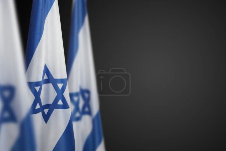 Israel flags with a star of David over dark gray background. Patriotic concept about Israel with national state symbols. Banner with place for text.