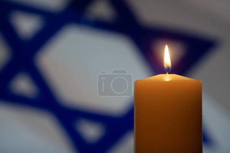 Burning candle on Israel flag background. Holocaust Remembrance Day.
