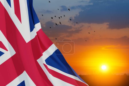 Téléchargez les photos : Drapeaux nationaux du Royaume-Uni avec des oiseaux volants sur fond de ciel couchant. Contexte avec place pour votre texte. - en image libre de droit