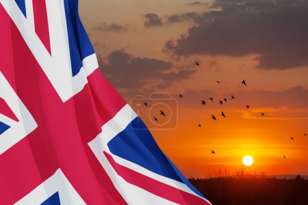 Téléchargez les photos : Drapeaux nationaux du Royaume-Uni avec des oiseaux volants sur fond de ciel couchant. Contexte avec place pour votre texte. Rendu 3d. - en image libre de droit