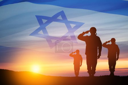 Silhouette von Soldaten, die gegen den Sonnenaufgang in der Wüste salutieren und Israel-Flagge. Konzept - Streitkräfte Israels.