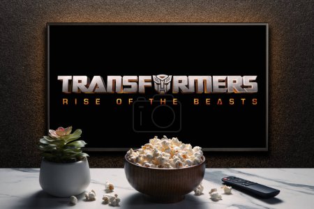 Photo for TV screen playing Transformers Rise of the Beasts trailer or movie. TV with remote control, popcorn bowl and home plant. Astana, Kazakhstan - May 15, 2023. - Royalty Free Image