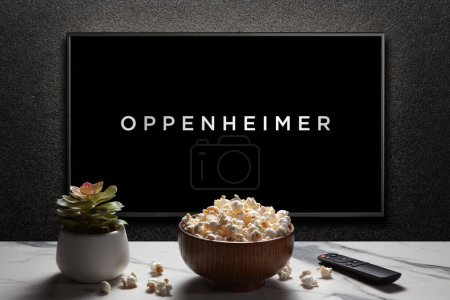 Photo for Oppenheimer trailer or movie. TV with remote control, popcorn bowl and home plant. Astana, Kazakhstan - July 2, 2023. - Royalty Free Image