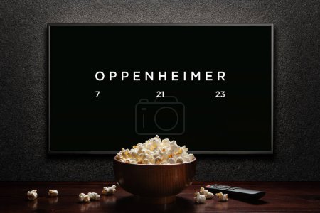 Photo for Oppenheimer trailer or movie. TV with remote control and popcorn bowl. Astana, Kazakhstan - July 2, 2023. - Royalty Free Image