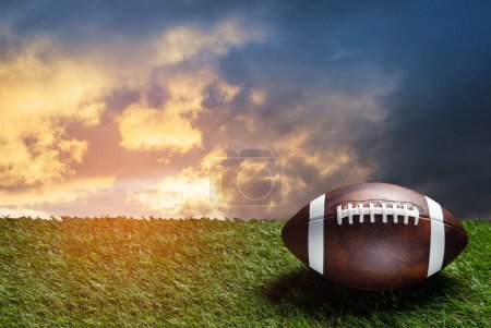 Foto de Pelota de fútbol americano en el campo de hierba verde en el fondo del cielo puesta del sol. Banner con espacio para texto. - Imagen libre de derechos