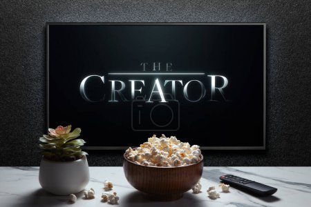 Photo for The Creator trailer or movie on TV screen. TV with remote control, popcorn bowl and home plant. Astana, Kazakhstan - September 23, 2023. - Royalty Free Image