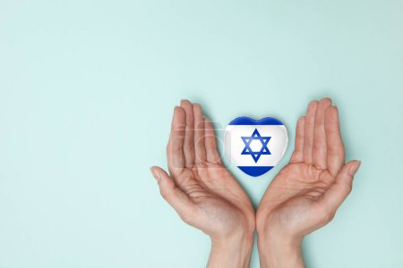 Herz mit Abdruck der israelischen Flagge in weiblichen Händen. Flach lag er. Kopierraum.