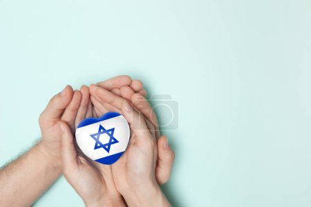 Herz mit Abdruck der israelischen Flagge in weiblichen und männlichen Händen. Flache Lage. Kopierraum.