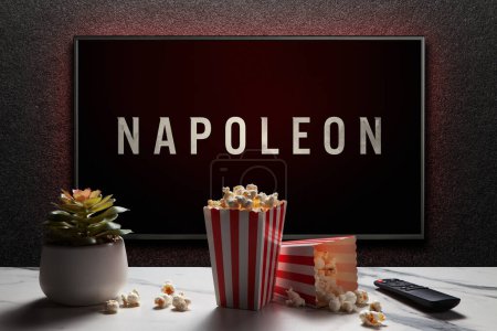 Photo for Napoleon trailer or movie on TV screen. TV with remote control, popcorn boxes and home plant. Astana, Kazakhstan - July 21, 2023. - Royalty Free Image