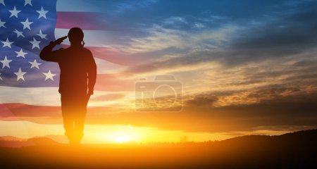 Téléchargez les photos : Silhouette de soldat saluant sur fond de coucher ou de lever du soleil et drapeau des États-Unis. Carte de souhaits pour la fête des anciens combattants, le jour du Souvenir, la fête de l'indépendance. Amérique célébration. - en image libre de droit