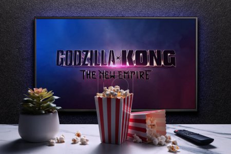 Photo for Godzilla x Kong The New Empire trailer or movie on TV screen. TV with remote control, popcorn boxes and home plant. Astana, Kazakhstan - March 22, 2024. - Royalty Free Image