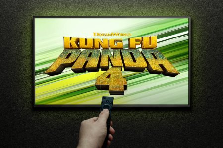 Téléchargez les photos : Kung Fu Panda 4 bande-annonce ou film à l'écran de télévision. L'homme allume la télé avec télécommande. Astana, Kazakhstan - 22 mars 2024. - en image libre de droit
