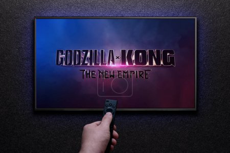 Photo for Godzilla x Kong The New Empire trailer or movie on TV screen. Man turns on TV with remote control. Astana, Kazakhstan - March 22, 2024. - Royalty Free Image
