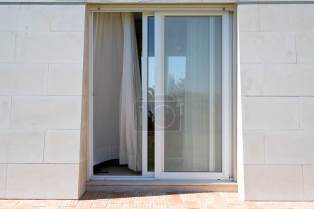 Outside facade of a home with sliding patio doors and a sloping wall