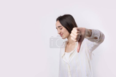 Photo for Young brunette in a blue tank top giving thumb down gesture looking with negative expression - Royalty Free Image