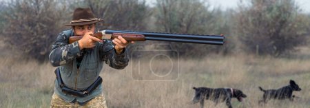 Téléchargez les photos : Homme chasseur en camouflage avec une arme à feu pendant la chasse à la recherche d'oiseaux sauvages ou de gibier. - en image libre de droit