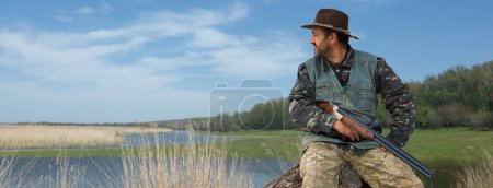 Homme chasseur en camouflage avec une arme à feu pendant la chasse à la recherche d'oiseaux sauvages ou de gibier.