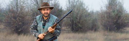 Homme chasseur en camouflage avec une arme à feu pendant la chasse à la recherche d'oiseaux sauvages ou de gibier.