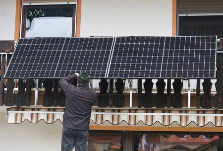 Foto de A man assembles a balcony power plant to generate electricity - Imagen libre de derechos