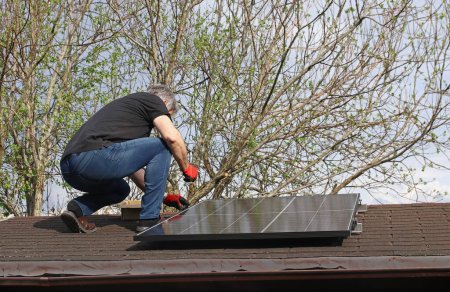 A man mounting a small solar system on a garden shed