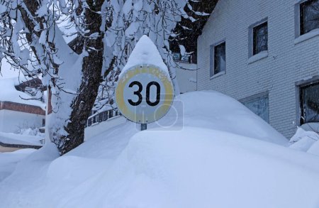 Foto de Una señal de tráfico cubierta de nieve con límite de velocidad 30 en invierno - Imagen libre de derechos