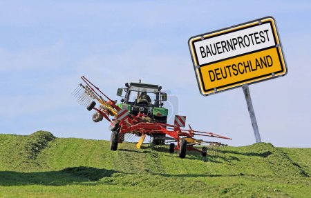 Téléchargez les photos : Signe avec protestation des agriculteurs Allemagne avec un tracteur fauchant le foin - en image libre de droit