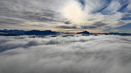 Drohnenschuss im Winter mit Nebel im Tal und Sonne in den Bergen