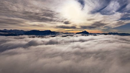 Drone shot in winter with fog in the valley and sun in the mountains