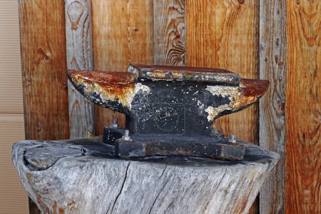 An old rusty anvil on a tree stump