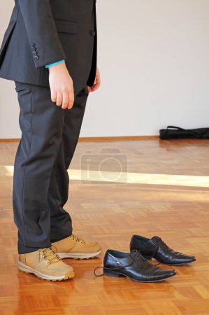 Téléchargez les photos : Un homme en costume se demande quelles chaussures il devrait porter. - en image libre de droit