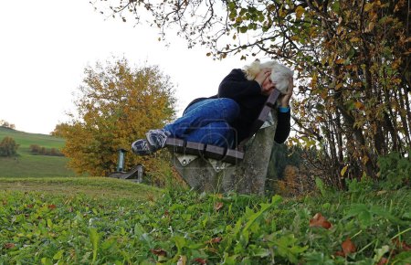 An elderly woman with depression sits sadly on a bench