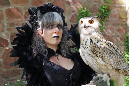 Fantasy figure. A woman dressed as a witch with an eagle owl on her hand