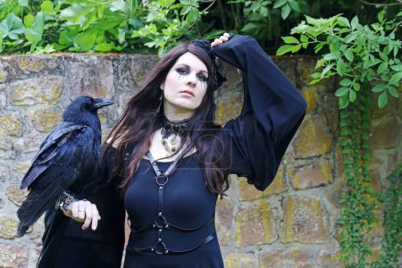 Téléchargez les photos : Une femme habillée en sorcière avec un grand corbeau sur la main - en image libre de droit