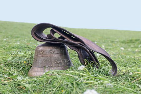 A large cowbell with leather strap on a mown meadow in Bavaria