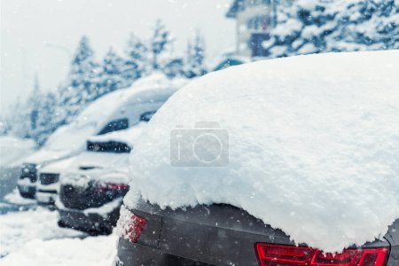 Foto de Plaza de aparcamiento de la calle de la ciudad con el coche SUV cubierto de nieve atrapado después de fuerte nevada nevada día de invierno por gran pila de nieve. Deriva de nieve y vehículos congelados. Condiciones meteorológicas extremas. - Imagen libre de derechos