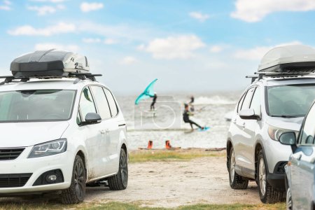 Frontansicht viele Autos mit Surfbrett-Kiteausrüstung am Sandstrand geparkt, Van Fahrzeug mit Dachbox Ocean Sea Beach Wassersport Spot Camp. Abenteuer Reisen Wassersport Aktivität.