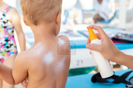 Photo for Mother applying sunscreen protection creme on cute little baby boy kid back. Mum using sunblocking lotion to protect baby from sun during summer sea vacation. Child healthcare travel vacation time. - Royalty Free Image