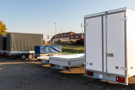 Many different types small passenger car cargo freight trailers parked in row at sale or rental site. Business and home transportation delivery. Service production and maintenance equipment.
