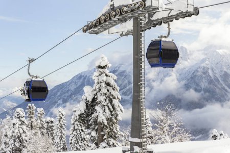 Photo for New modern spacious big cabin ski lift gondola against snowcapped forest tree and mountain peaks covered in snow landscape in luxury winter alpine resort. Winter leisure sports, recreation and travel. - Royalty Free Image