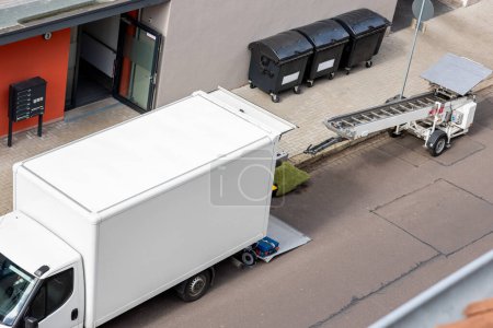 Mover service lifting ladder cargo crane platform vehicle van parked at city street. Retractable furniture elevator machine car pickup truck rental company for relocation and house moving delivery.