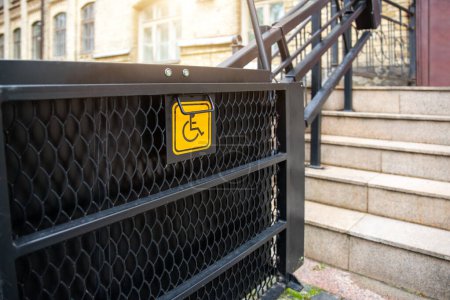 Photo for Electric platform lift at building staircase for disabled people with wheelchair sign plate on old city street. Elevator stairlift ramp mechanism for senior disability people. Medical urban equipment. - Royalty Free Image