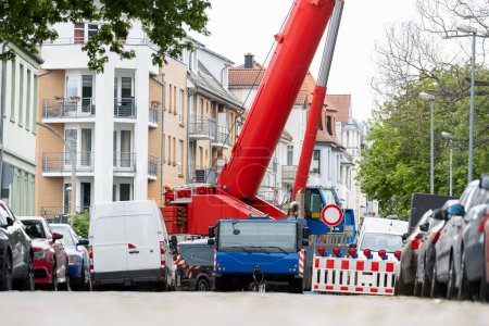 Extraschwere Last Mobilkran arbeitet auf engen europäischen Altstadtgassen Hintergrund. Teleskopausleger Hebezeuge Baustellenvermietung. Schwere industrielle Maschinen.