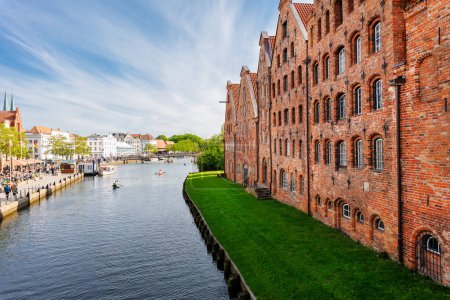 Scenic view panorama Lubeck hanseatic city blue sky sunny summer day. Travemunde Trave river embankment in Lubeck historic Holstentor museum Salzspeicher building in medieval town altstadt Germany.