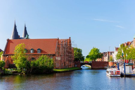 Scenic view panorama Lubeck hanseatic city blue sky sunny summer day. Travemunde Trave river embankment in Lubeck historic Holstentor museum Salzspeicher building in medieval town altstadt Germany.