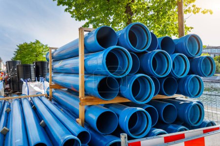 Primer plano azul PVC tuberías de fontanería apiladas paletas de madera de reemplazo en la ciudad alemana obras de construcción de infraestructuras de la calle. Edificio urbanístico fondo industrial.