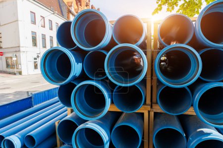 Primer plano azul PVC tuberías de fontanería apiladas paletas de madera de reemplazo en la ciudad alemana obras de construcción de infraestructuras de la calle. Edificio urbanístico fondo industrial.